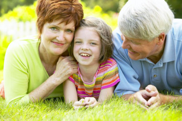 vibrant grandparents and young girl laying in grass 02252014